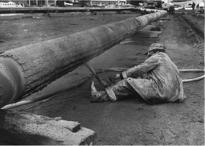 Image Photo  1963 - A workman applies a concrete coating to one of the pipes from Fawley to London to protect them from any damage which may occur on the river bed.