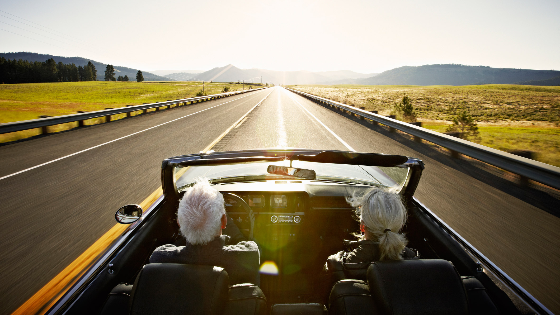 couple driving into sunset in a convertible
