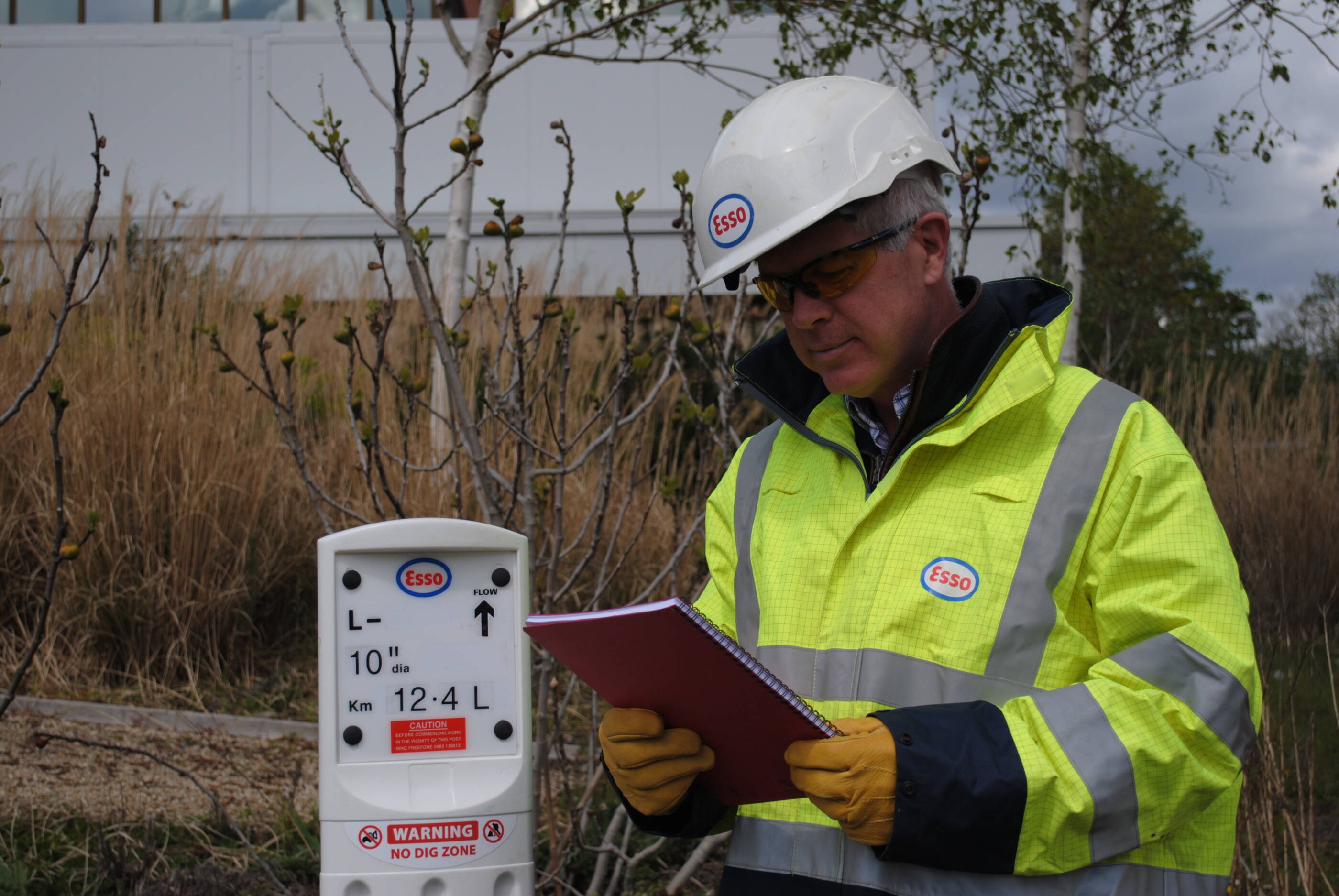 ExxonMobil employee looking at notebook outdoors.